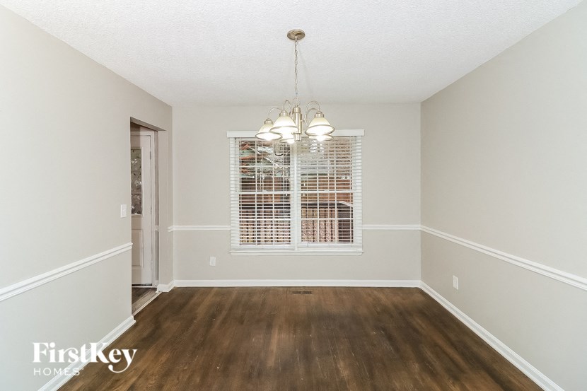 an empty dining room with a window and a chandelier