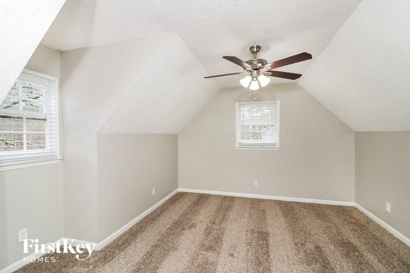 a spacious attic room with a ceiling fan and carpet