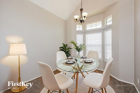 A dining room with a glass table and white chairs.