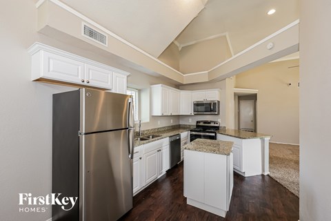 A kitchen with a stainless steel refrigerator and white cabinets.