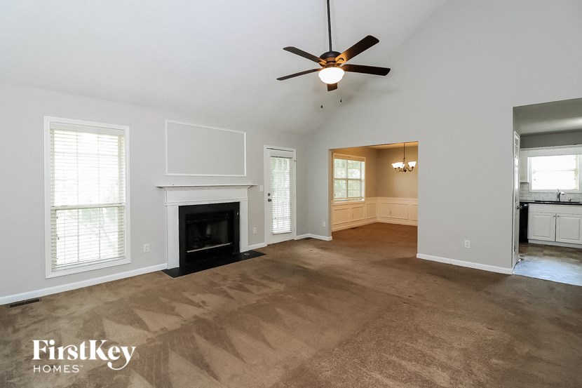 an empty living room with a fireplace and a ceiling fan