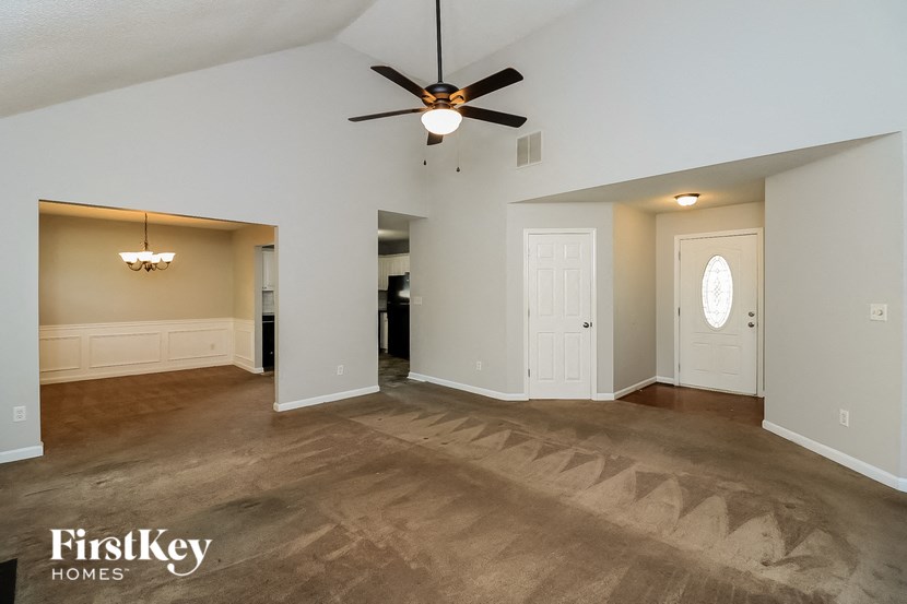 an empty living room with a ceiling fan