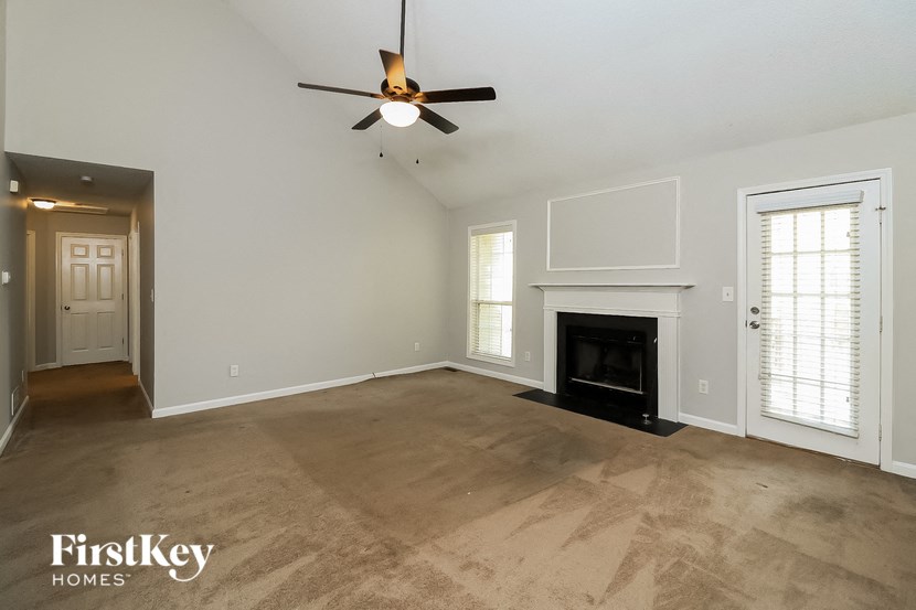 an empty living room with a fireplace and a ceiling fan