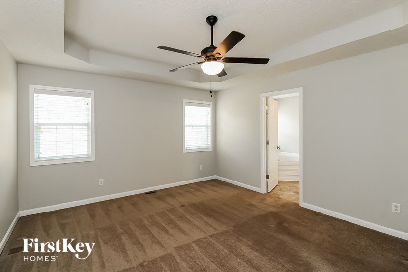 an empty living room with a ceiling fan and a door to a closet