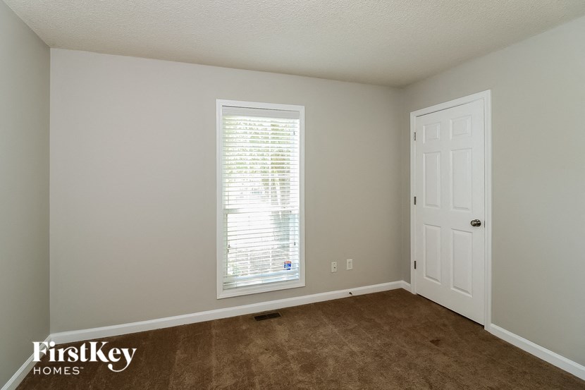 the bedroom of a home with a white door and a window