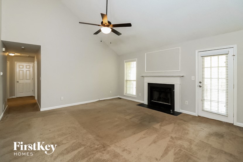 an empty living room with a fireplace and a ceiling fan