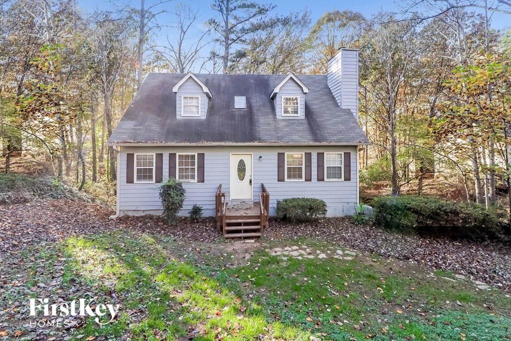 A small house with a porch and a tree in front.