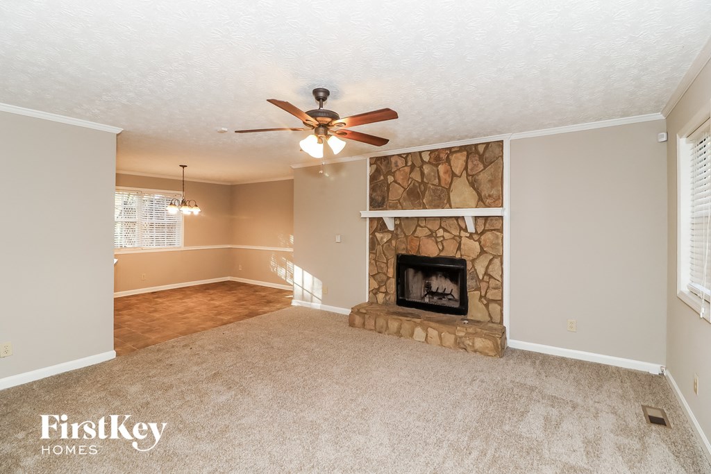 A living room with a fireplace and a ceiling fan.