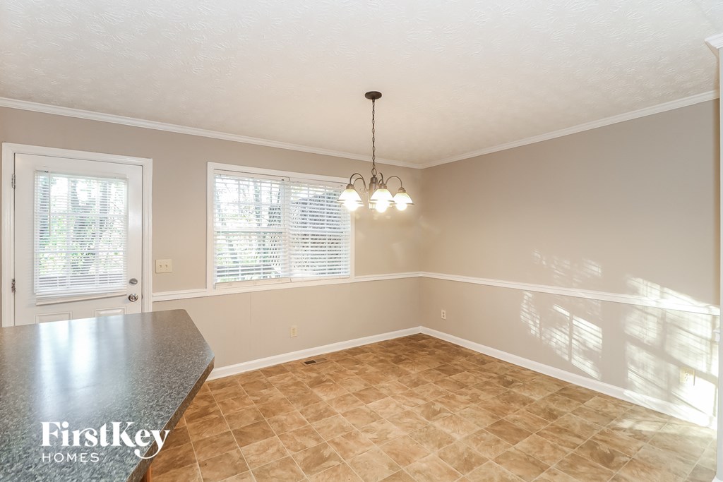 A sunny room with a tiled floor and a chandelier hanging from the ceiling.