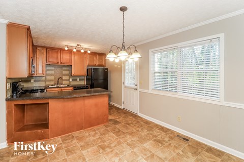 A kitchen with brown cabinets and a black refrigerator.