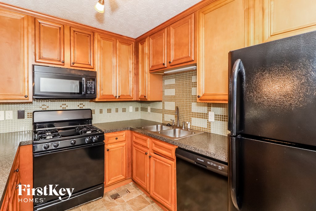 A kitchen with wooden cabinets and black appliances.