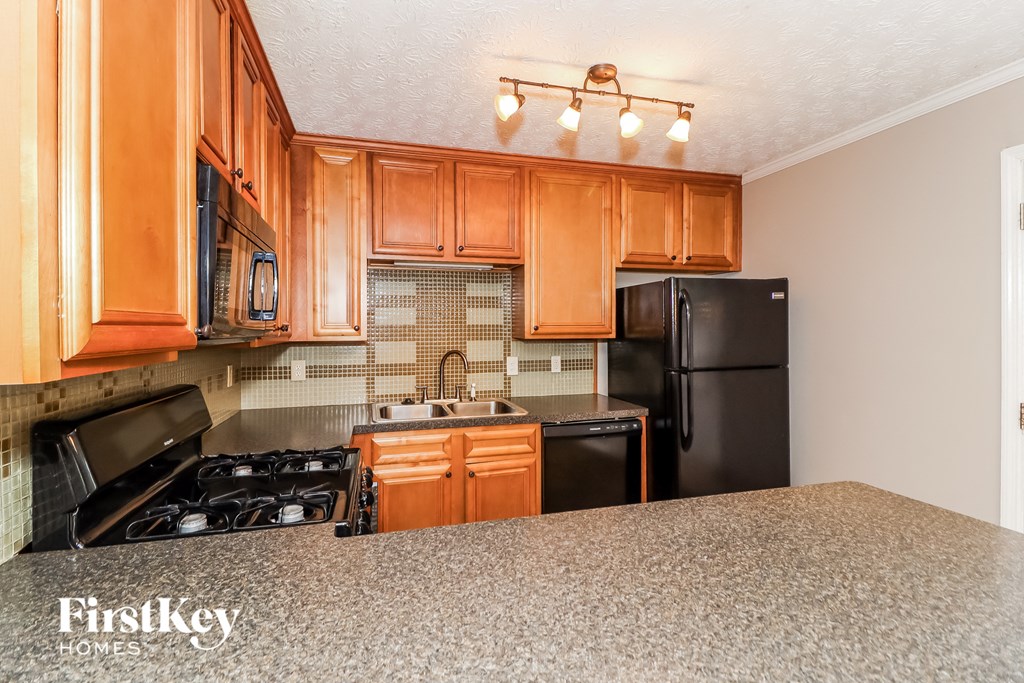 A kitchen with wooden cabinets and black appliances.