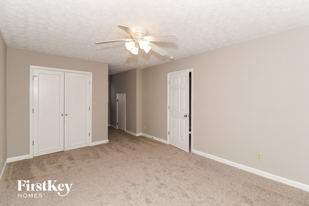 A spacious room with a ceiling fan and two doors.