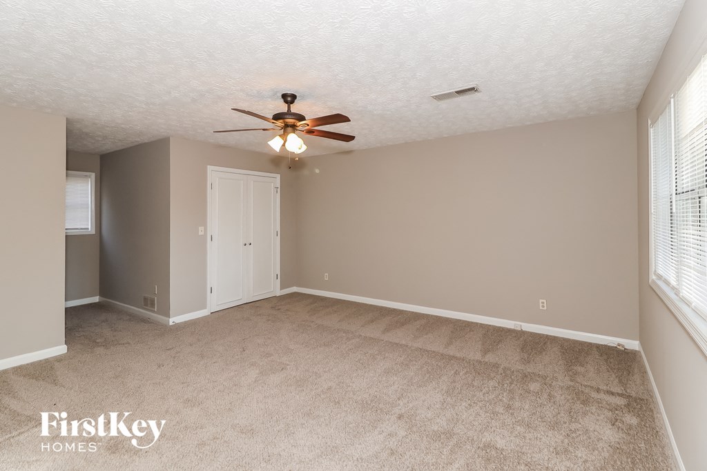 A room with a ceiling fan and carpeted floor.