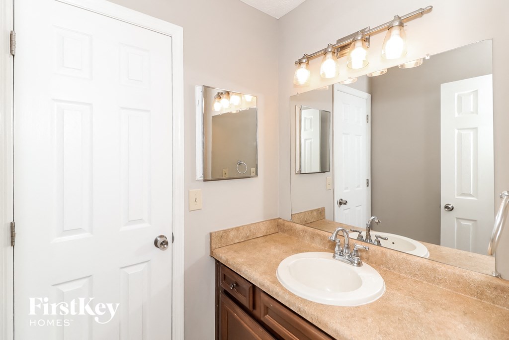 A bathroom with a sink, mirror, and lights.