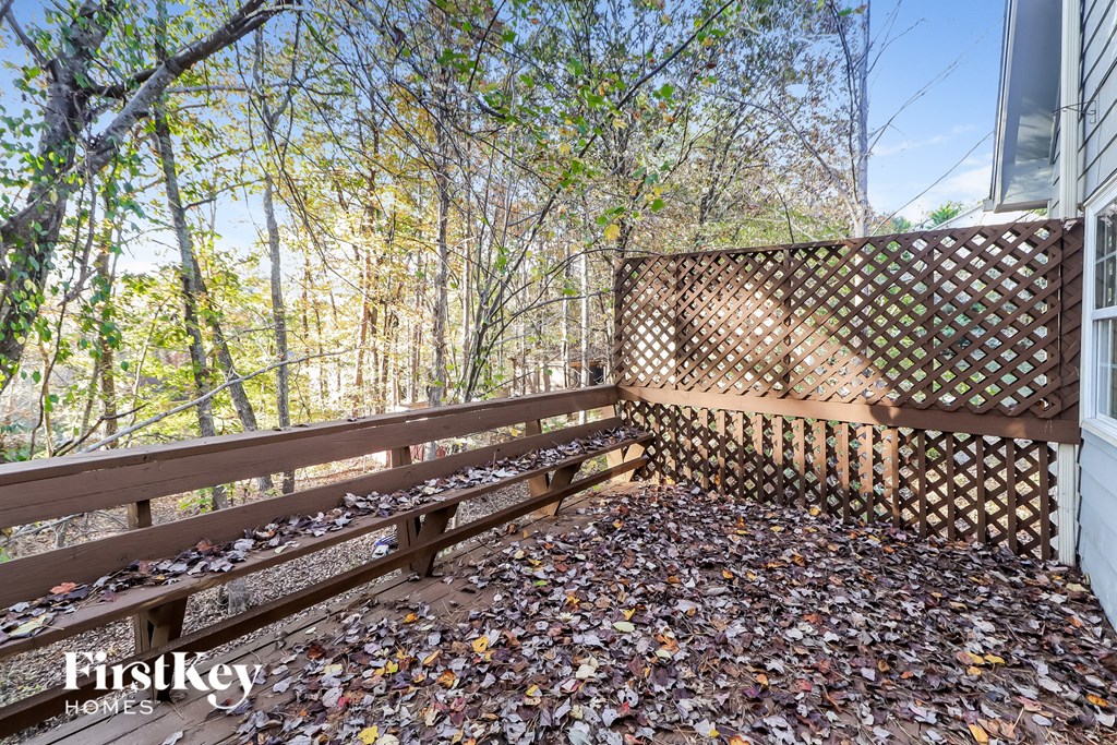 A wooden deck with a lattice fence and fallen leaves on the ground.