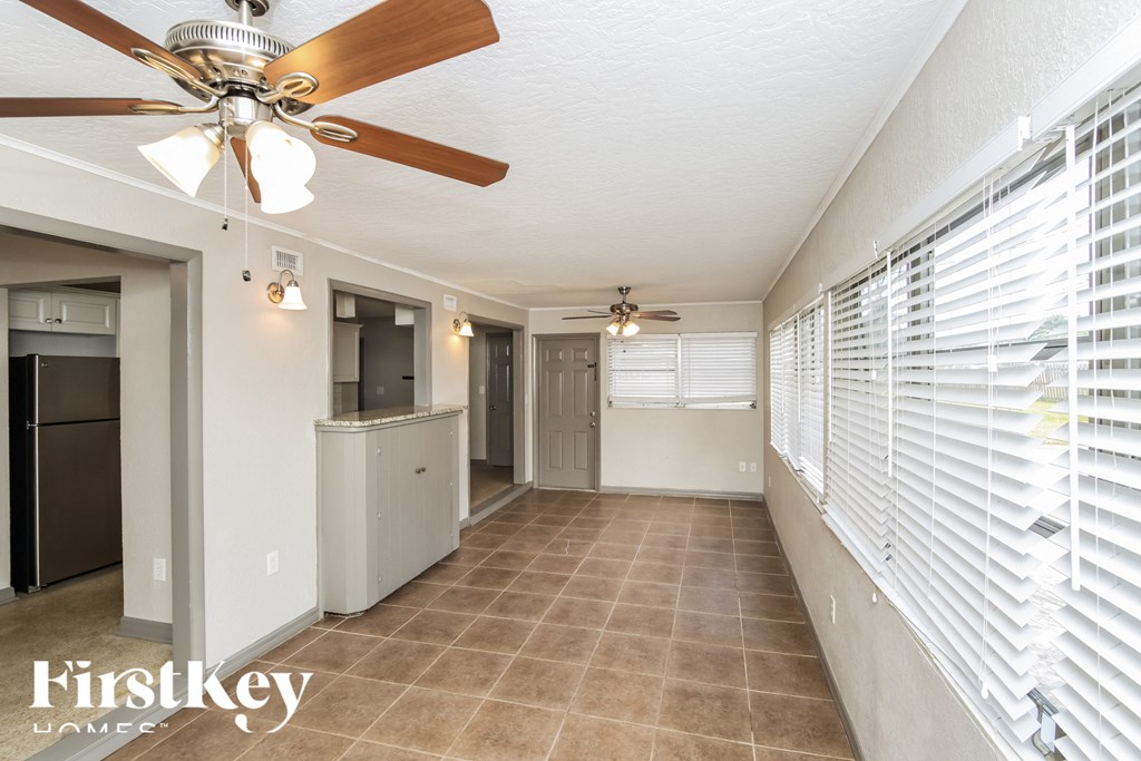 a kitchen and living room with white blinds and a ceiling fan