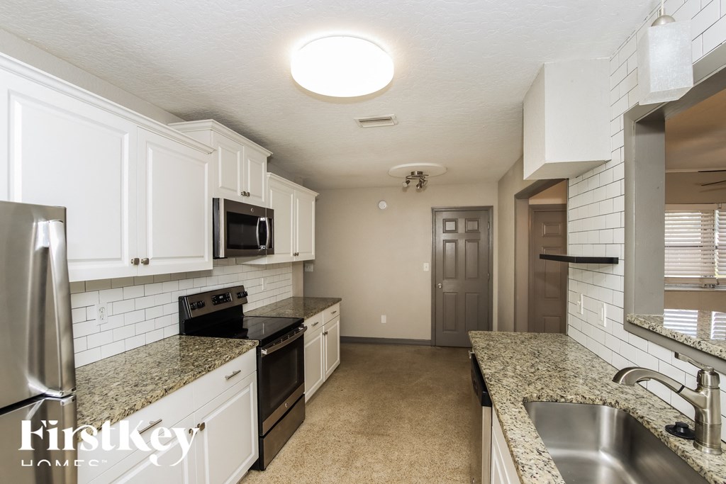 a kitchen with white cabinets and granite counter tops