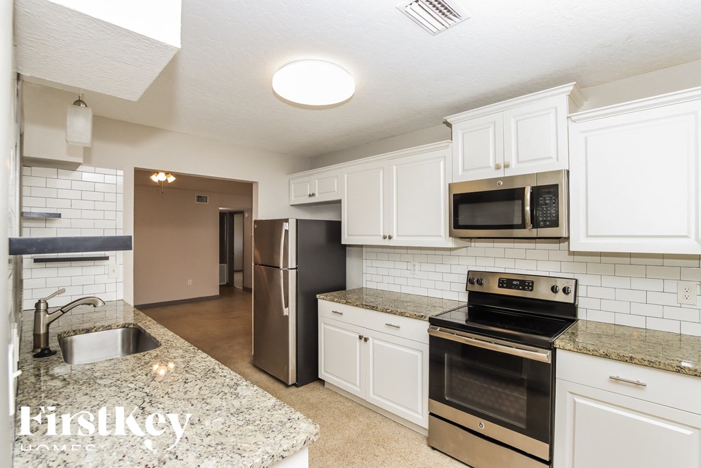 a kitchen with white cabinets and granite counter tops