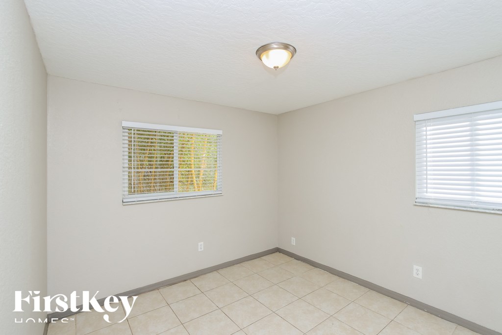 a small room with a tiled floor and two windows