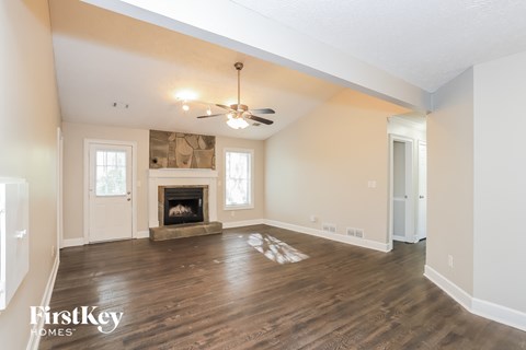 A spacious living room with a fireplace and a ceiling fan.