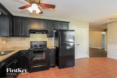 A kitchen with black cabinets and a black fridge.