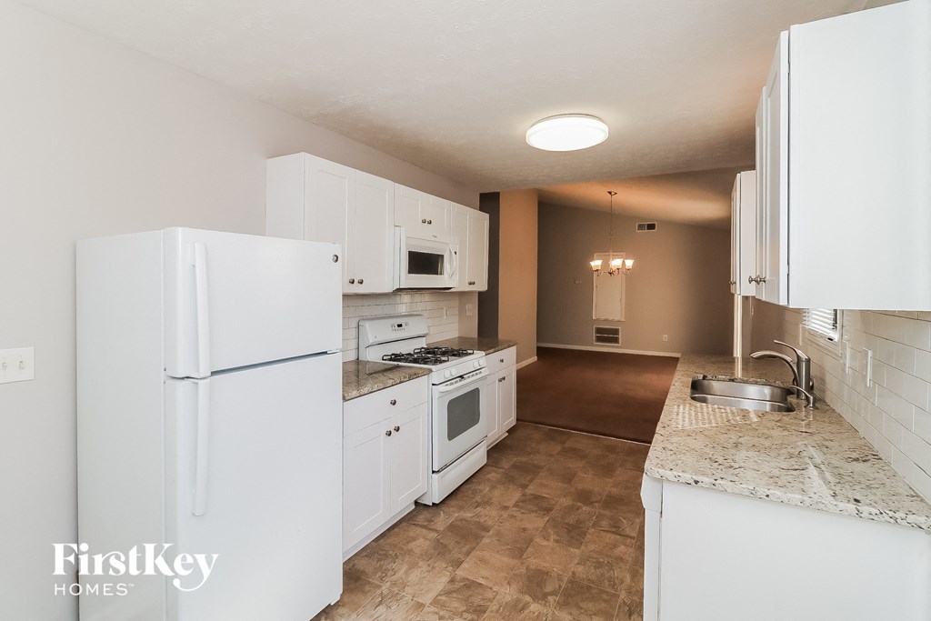 a kitchen with white cabinets and appliances and a white refrigerator