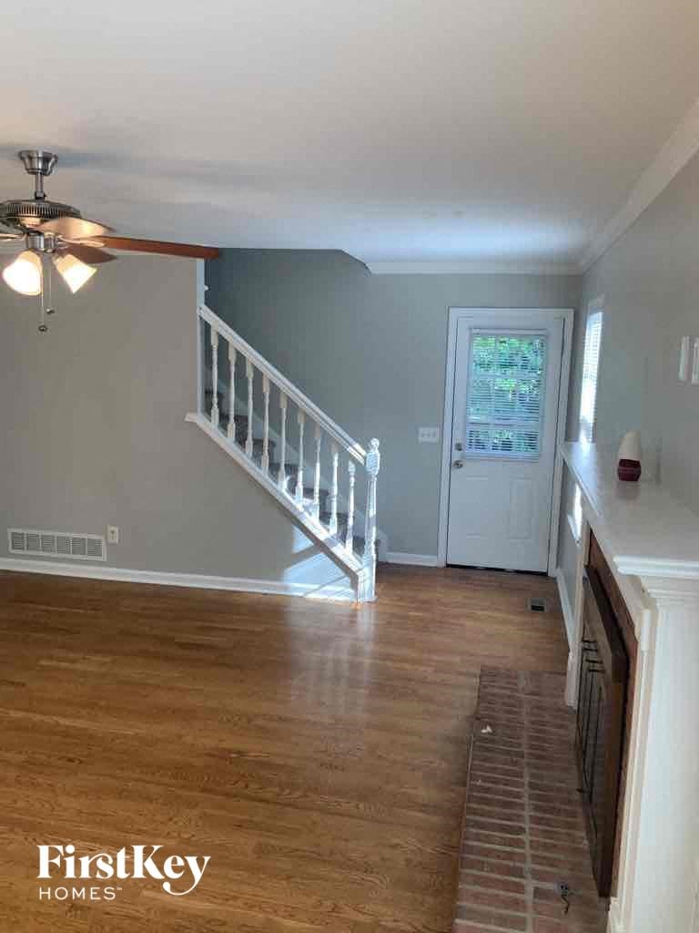a living room with a staircase and a door to a room with wood floors