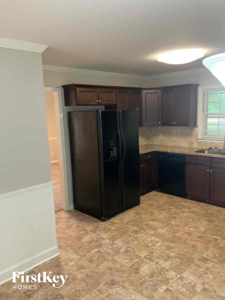 an empty kitchen with a black refrigerator in it