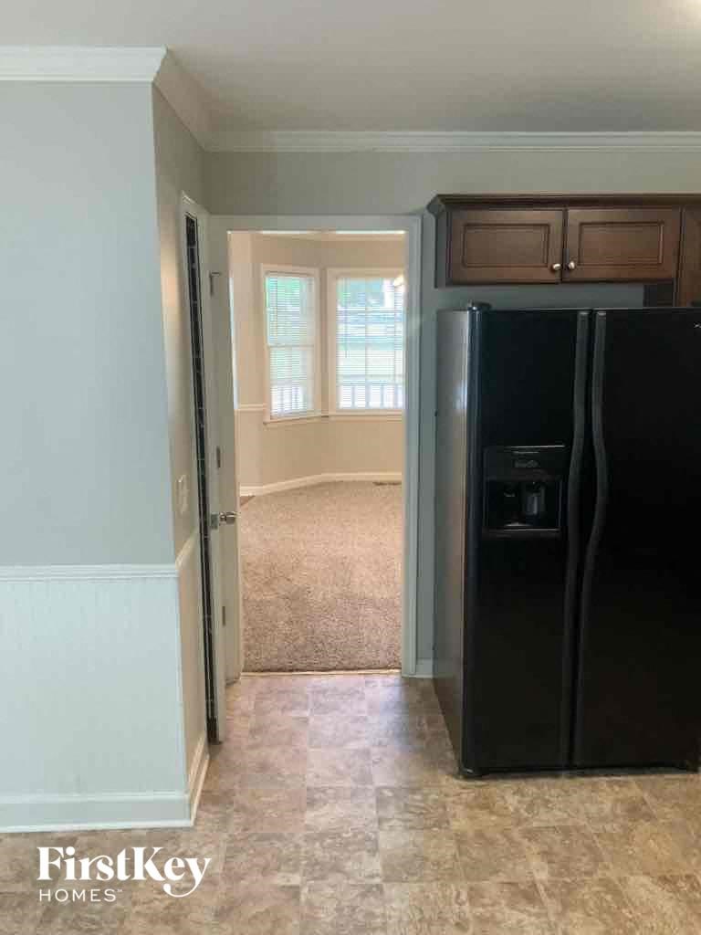 an empty kitchen with a black refrigerator and a window