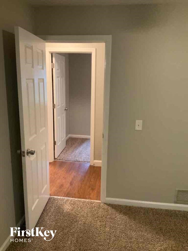 an empty room with a door open to a hallway and a door to a bedroom