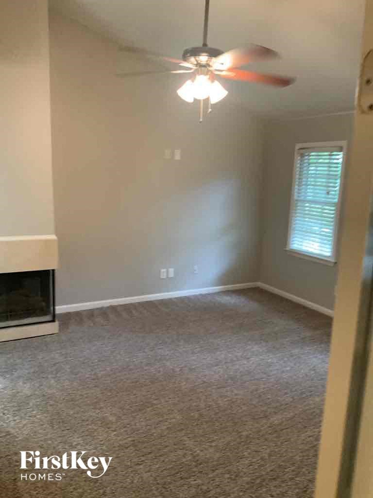an empty living room with a ceiling fan and a fireplace
