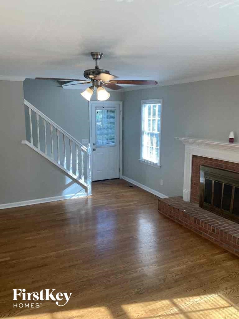 an empty living room with a ceiling fan and a fireplace