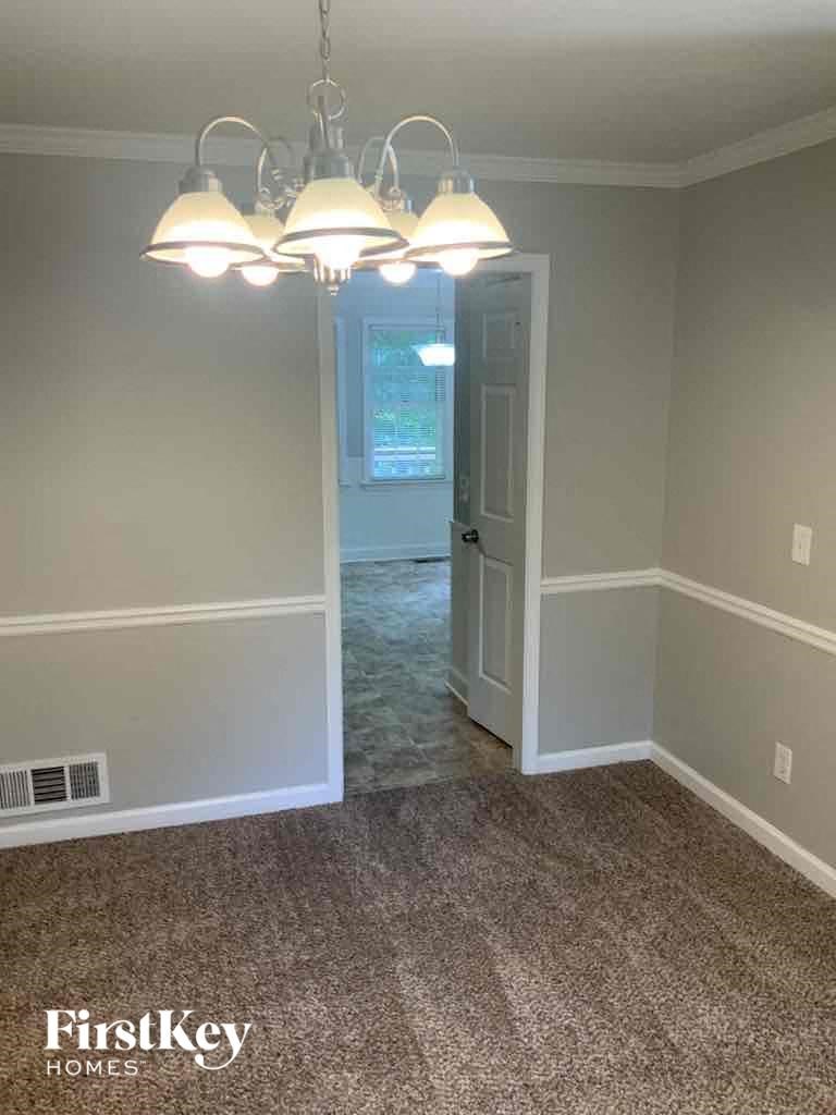an empty living room with a chandelier and a door to a bedroom