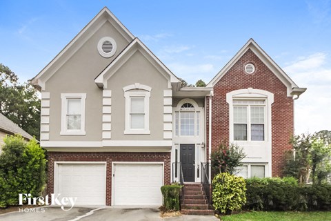 a brick house with two garage doors and a lawn