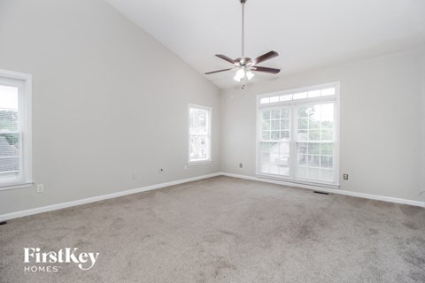 an empty living room with a ceiling fan and a window