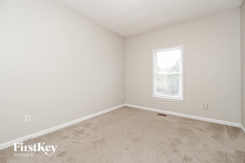 a bedroom with white walls and carpet and a window