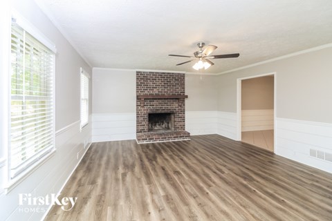 A spacious room with a fireplace and a ceiling fan.