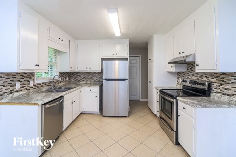 A kitchen with white cabinets and a marble countertop.