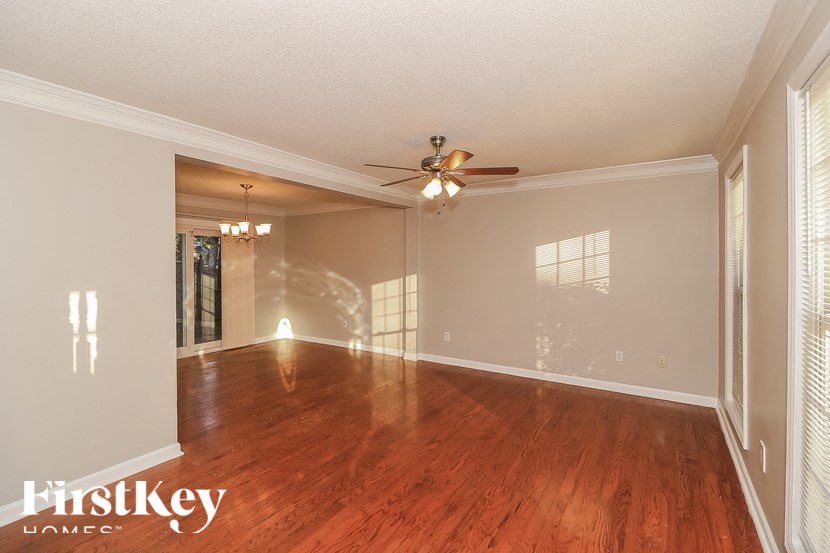 an empty living room with a ceiling fan and wood floors
