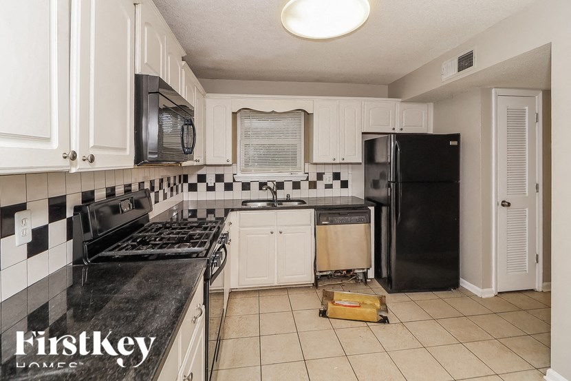 a kitchen with white cabinets and a black refrigerator