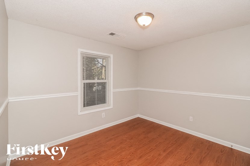 a bedroom with wood flooring and white walls and a window