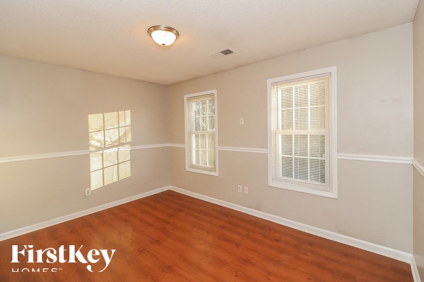 an empty living room with wood flooring and three windows