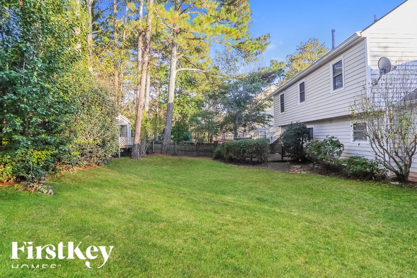 a backyard with a white house and a green lawn
