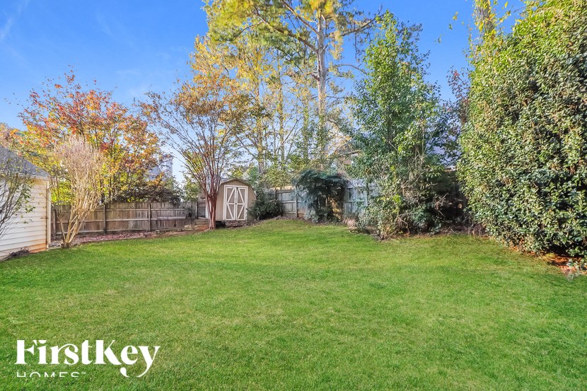 a backyard with a green lawn and a fence