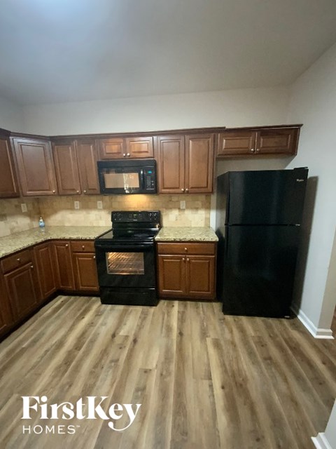 A kitchen with wooden cabinets and a black refrigerator.