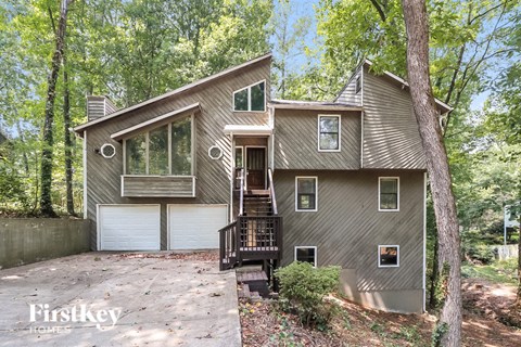 front view of a gray house with a driveway and trees