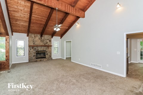 a living room with a stone fireplace and a carpeted floor