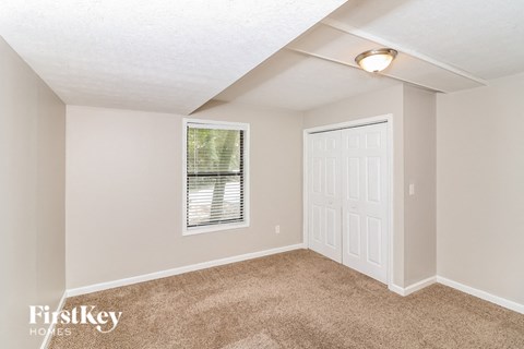 a bedroom with carpet and a white door and a window
