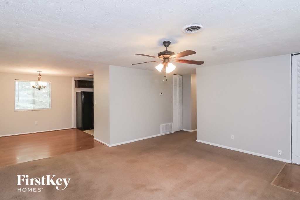 A spacious room with a ceiling fan and lighting fixture.